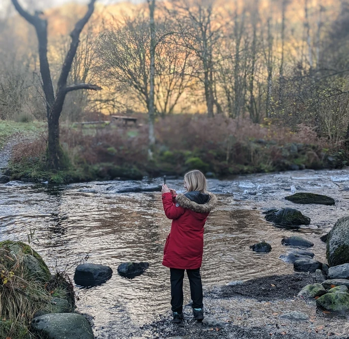 Helen at Core Social creating social media content at a stream using her phone